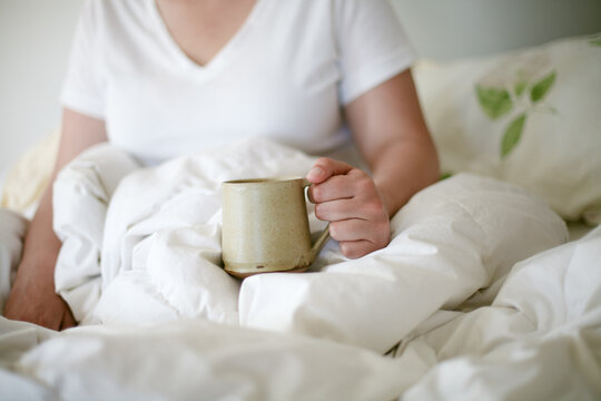 Woman holding coffee mug in bed