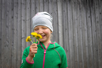 Portrait of beautiful girl outdoors with flowers against old wooden hut