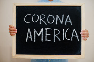 Fototapeta premium Corona America. Coronavirus concept. Boy hold inscription on the board.