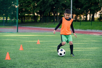 Soccer player kicking ball on field. Soccer players on training session. Teen footballer kicking...