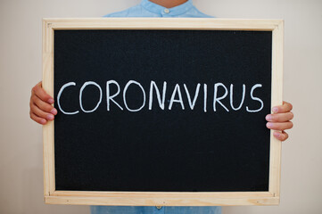 Coronavirus concept. Boy hold inscription on the board.