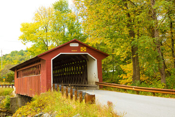 Silk Road covered bridge with trees showing fall colors near Paper Mill Village, Vermont.
