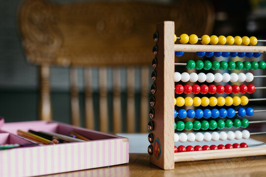 Box with crayons and abacus on a desk in a classroom