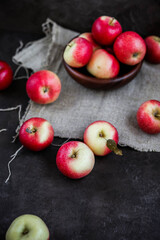 Lots of small apples in wooden bowls. Autumn harvest of fruits on a dark background.