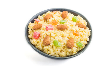 Millet porridge with candied fruits and almonds in blue ceramic bowl isolated on white background. Side view, close up.