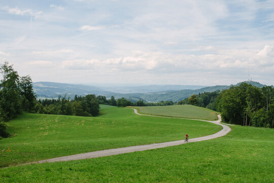 male rides bike down winding road in switzerland