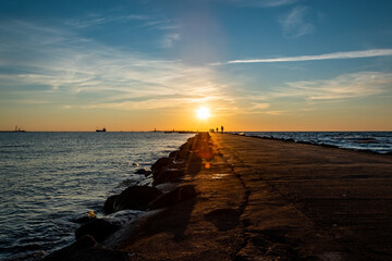 Obraz premium Colourful sunset with golden sun rays on the sea. View on the pier and the bay.