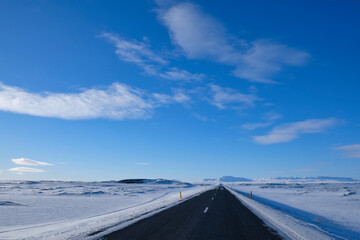 
Straight road to nowhere in winter in Iceland with a blue and sunny sky.