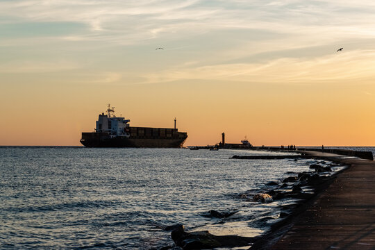 Global shipping and worldwide business. Container ship passes through the lighthouse for going to the open sea.