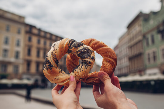 Couple of tourists holding bagels obwarzanek traditional polish cuisine snack on Market square in Krakow. Travel Europe