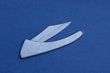 one gray metal folding knife lies on a blue table