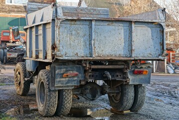 Obraz premium one big old gray truck stands on the street in a puddle on the road