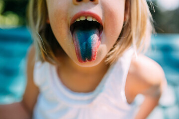 Little girl with blue tongue from sucking on lolipop