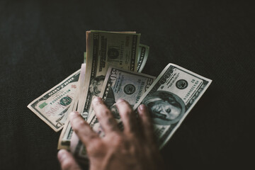 Hand touching a stack of US dollar bills.