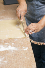 unrecognizable person cutting flour dough on granite plateau or table in the kitchen to bake