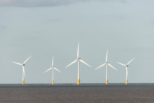 Five wind turbines in a row at sea
