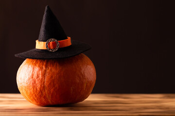 Halloween orange pumpkin in a witch hat on a brown background. Copy space.