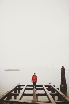man in red coat on an old bridge