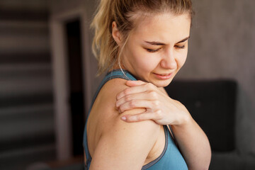 Fototapeta na wymiar Women wearing athletic suits feeling shoulder pain after exercise at home. The danger of self-training