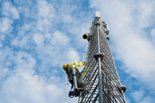Working at heights, technician climbs up on a communications tower