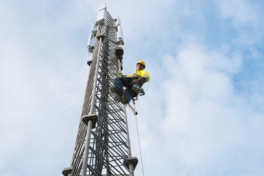 Working at heights, technician climbs up on a communications tower