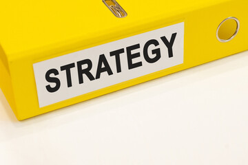 The word strategy on a white background with a yellow folder. Business concept