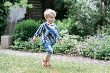 3 year old happy boy walking in a garden