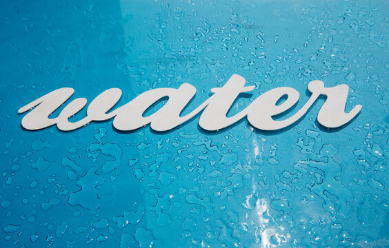 Water written on a surface with water drops on it