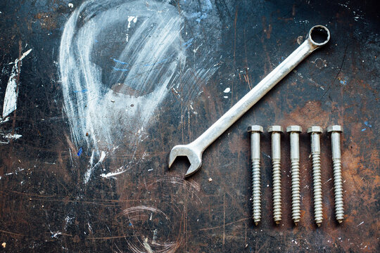 Screw bolts and wrench on worn work table