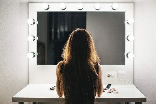 Vew from behind of a woman making her face in a dressing room