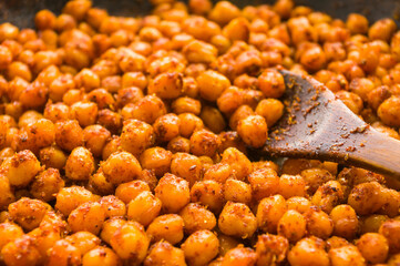 Cooking chickpeas with spices in a pan, close-up