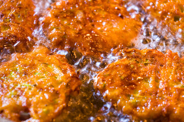 Fried vegetable fritters with zucchini, carrots, herbs, eggs, and cheese in boiling oil.