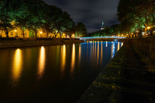 The night view of Aura river in Turku, Finland with a clock tower of cathedral and bridge on a background.