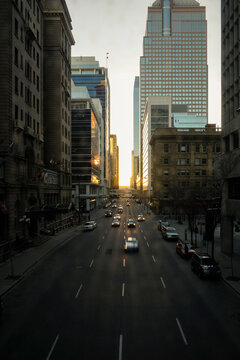 A downtown street with oncoming traffic at sunset