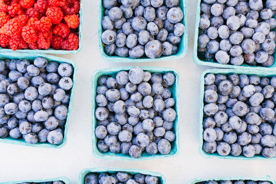 Pints filled with fresh whole blueberries and raspberries at market