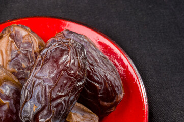 Big luxury dried date fruit in bowls on the dark surface, kurma ramadan kareem concept, close up.