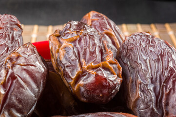 Big luxury dried date fruit in bowls on the bamboo mat, kurma ramadan kareem concept, close up.