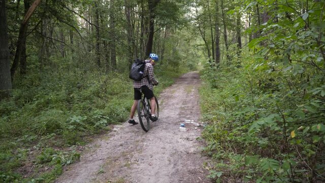 Man ride bicycle through forest, collecting trash. Trendy sports programs plogging that help preserve environment. Pollution. Ecological problem. Plastic ban awareness, national cleaning day concept