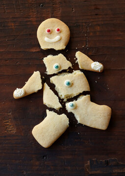 Broken sugar cookie man on dark wood surface