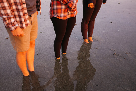 three friends together on beach with feet stuck in sand