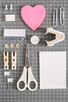 White office tools and pink notepad on grey background