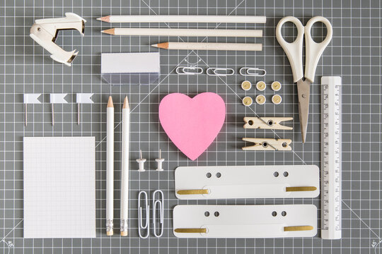 White office tools and pink notepad on grey background