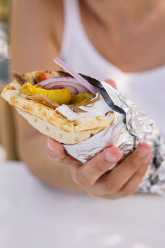 A woman holding fresh greek gyro with vegetables and meat