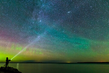 Boy Shining Flashlight Into Night Sky With Perseids Meteor Shower Milky Way and Northern Lights