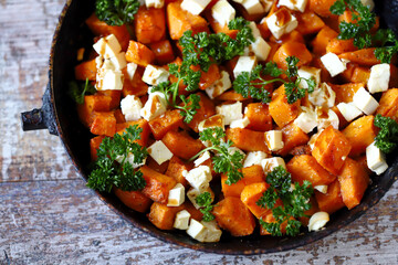 Baked pumpkin with feta cheese in a frying pan. Healthy autumn food. Thanksgiving Day. Selective focus. Macro.