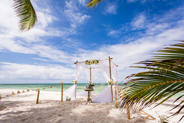 Wedding bamboo gazebo, decorated with tropical flowers and coloured fabrics on the paradise beach with palm trees, white sand and blue water of Caribbean Sea, Punta Cana, Dominican Republic 