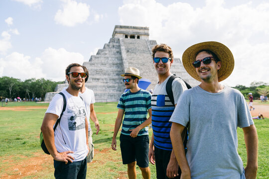 Group of men friends having fun next to Kukulkan pyramid in Chichen Itza, Mexico