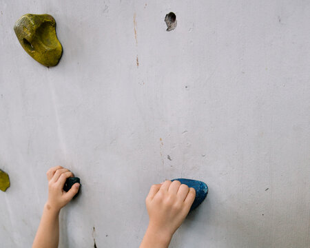 Hands of a very young kid practicing to be a rock climber