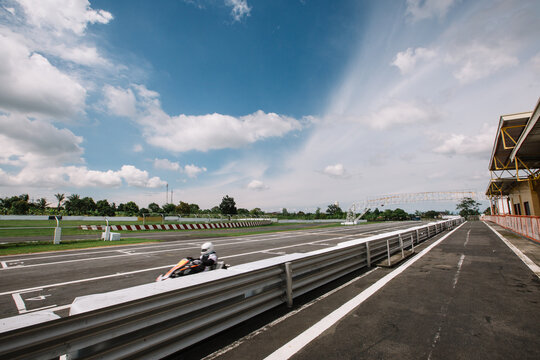A kart driver zooms past near the start/finish line in racing circuit