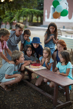 Group of ten children celebrating a birthday with cake